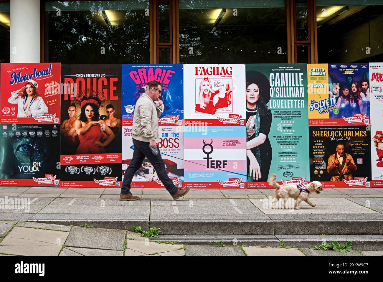 Uomo che cammina un cane pastposter che pubblicano gli spettacoli dell'Edinburgh Fringe Festival a George Square, Edimburgo, Scozia, Regno Unito. Foto Stock