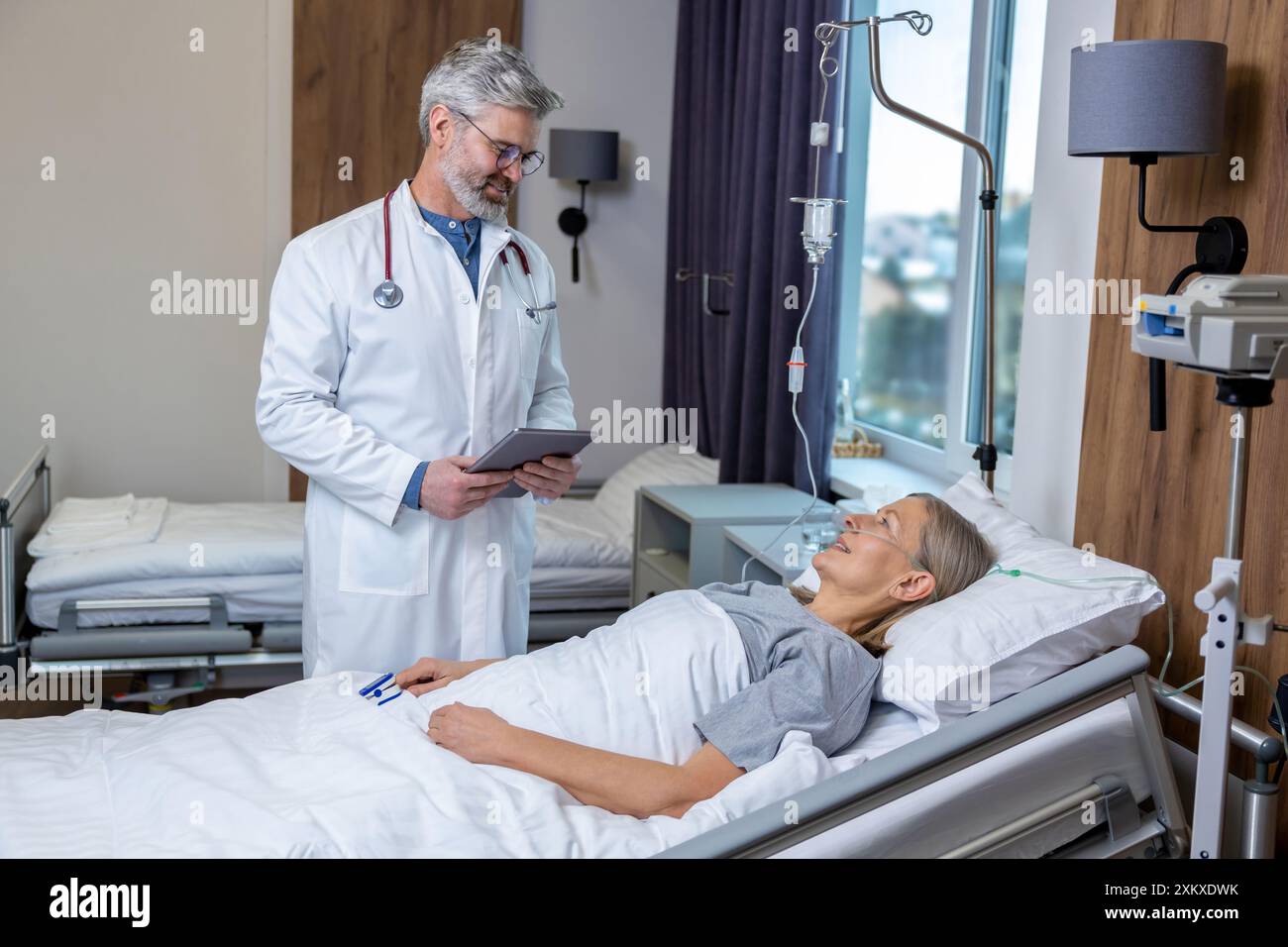 Medico che redige un elenco di prescrizioni per un paziente in un reparto di terapia intensiva Foto Stock