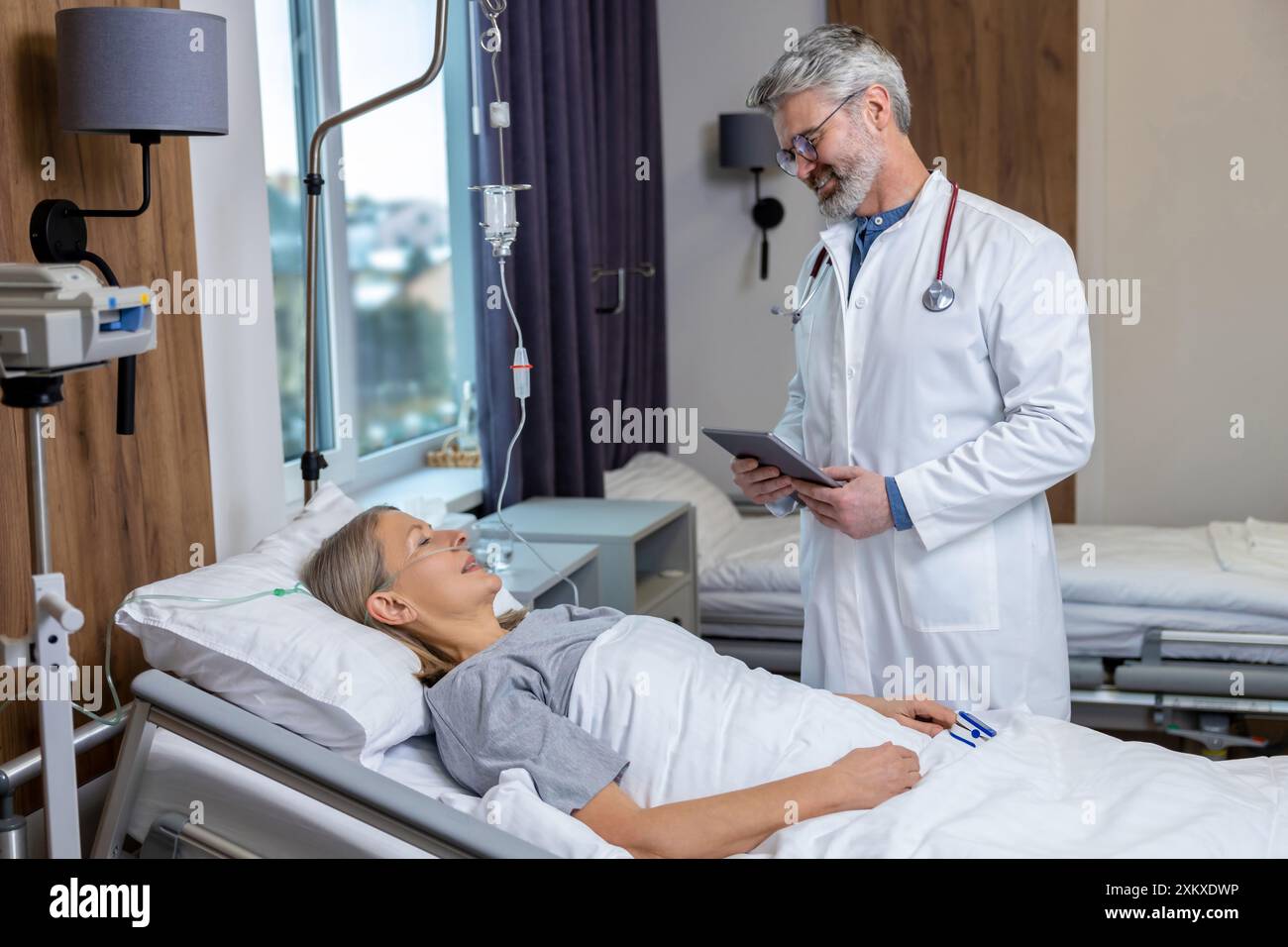 Medico che redige un elenco di prescrizioni per un paziente in un reparto di terapia intensiva Foto Stock