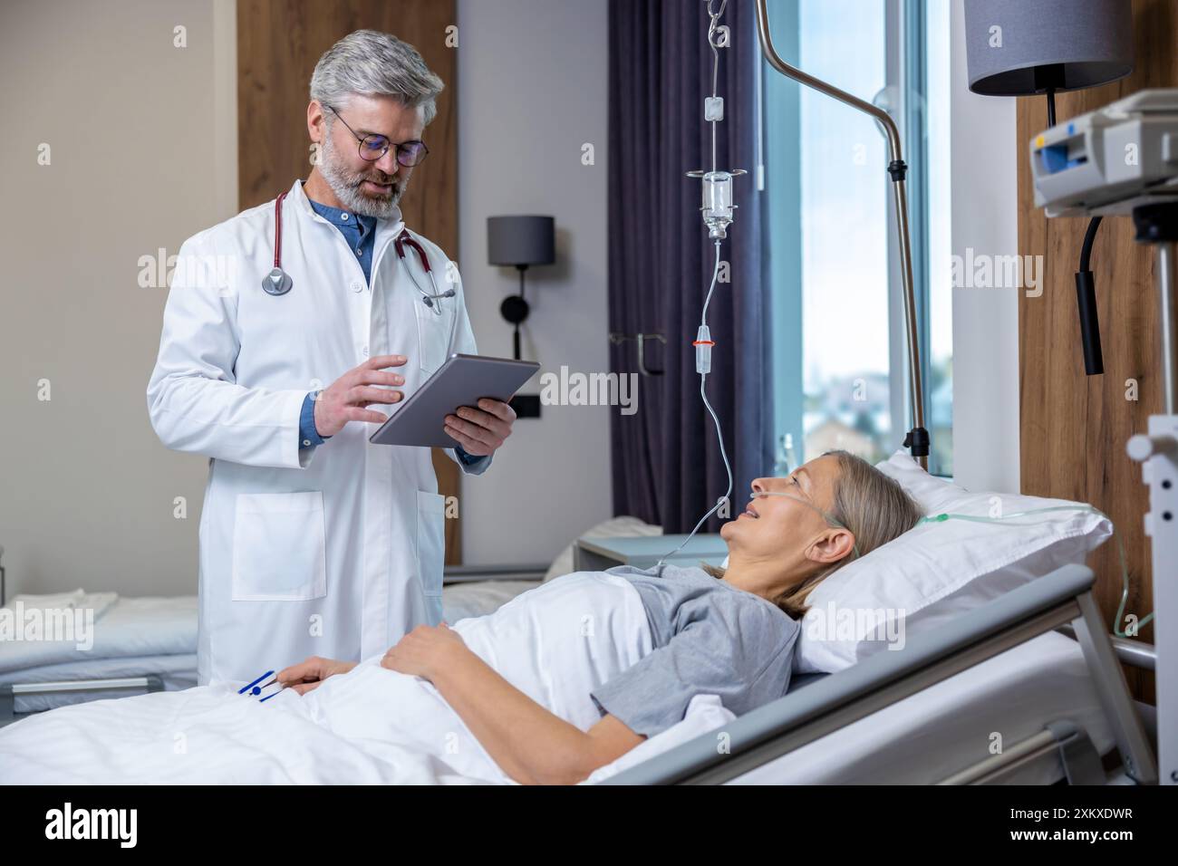 Medico che redige un elenco di prescrizioni per un paziente in un reparto di terapia intensiva Foto Stock
