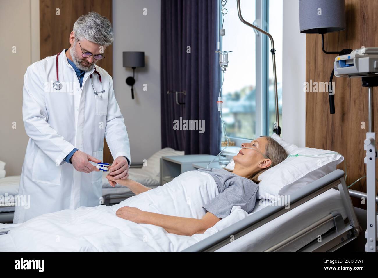 Medico che redige un elenco di prescrizioni per un paziente in un reparto di terapia intensiva Foto Stock