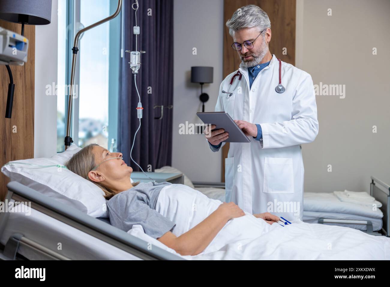 Medico che redige un elenco di prescrizioni per un paziente in un reparto di terapia intensiva Foto Stock