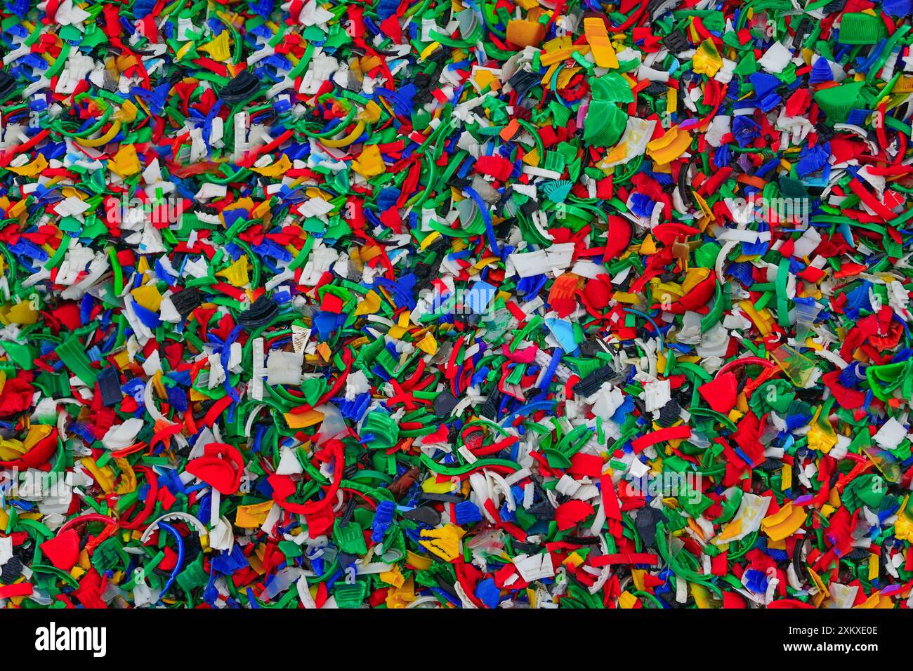 Processo di riciclaggio della plastica, bottiglia di plastica schiacciata o piccoli pezzi di bottiglie di plastica colorata tagliate, riciclaggio di fiocchi di bottiglie, triturazione di plastica Foto Stock