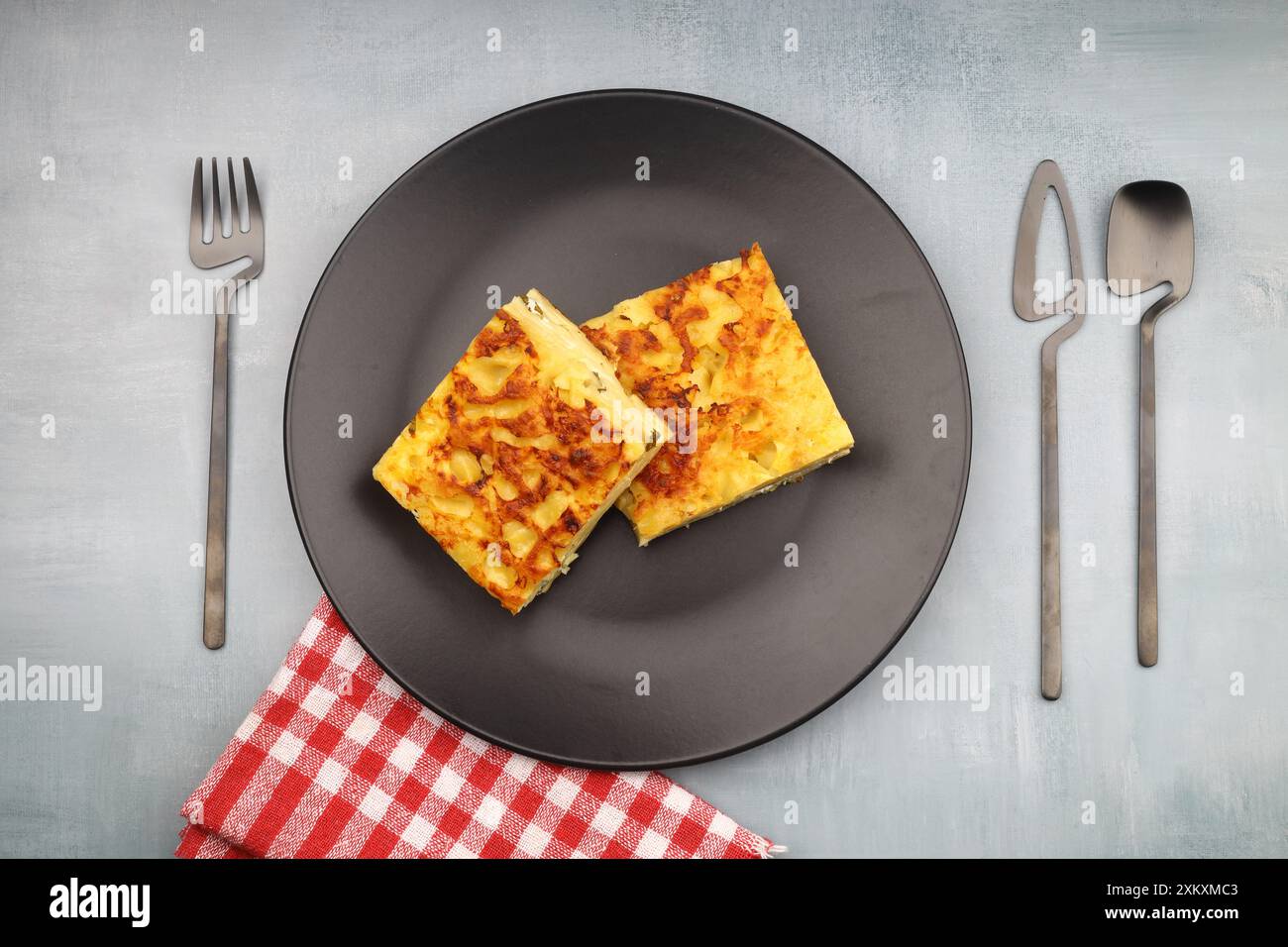 Fette di torta di formaggio Round Borek al forno nel vassoio della cucina con erbe. Sfondo scuro. Vista dall'alto. Spazio di copia Foto Stock