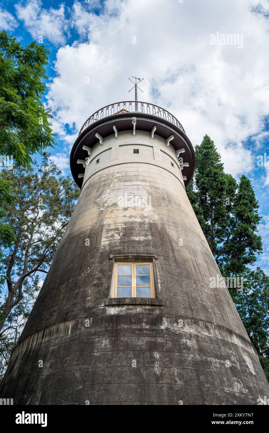 Una vista, guardando su di un cielo nuvoloso e blu, dell'Osservatorio Old Windmill sulla Wickham Terrace incorniciata dal fogliame degli alberi verdi del parco. Foto Stock