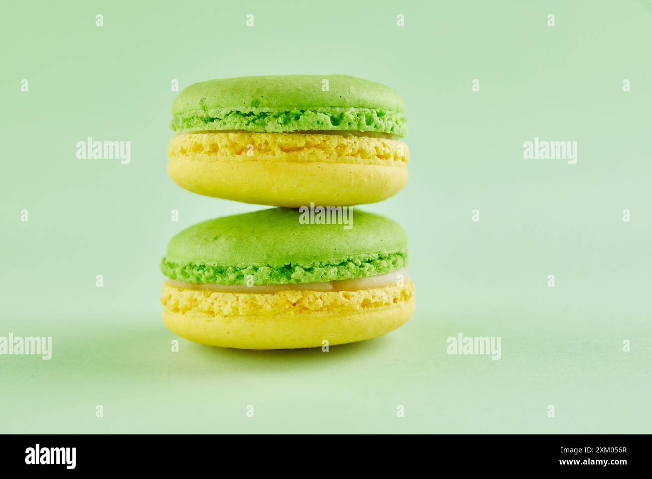 Macaron verdi e gialli abbinati a spicchi di lime e cioccolato bianco, accanto a un margarita con bordo salato. Foto Stock