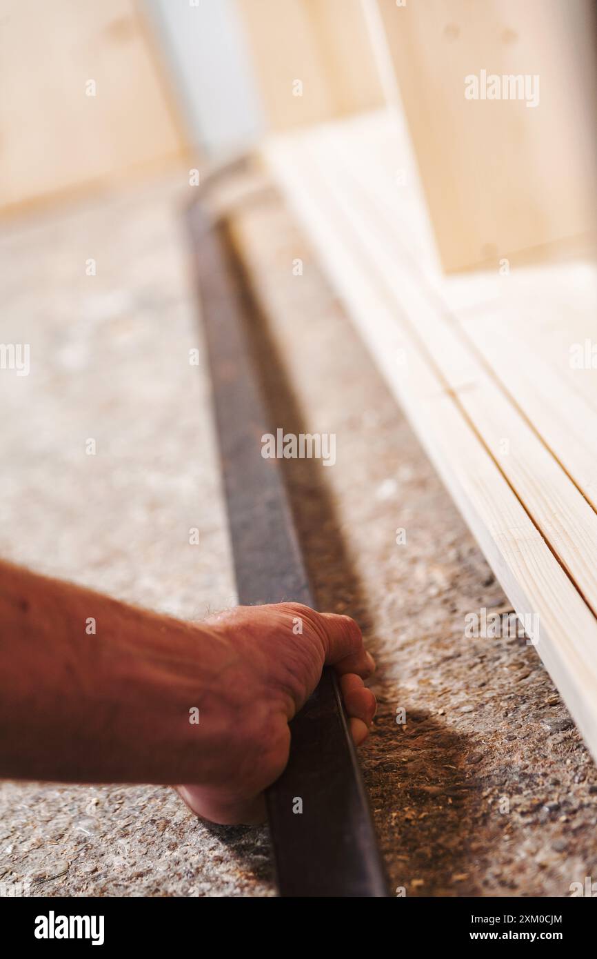 Falegname che misura il legno in un'officina con precisione e cura, creando un lavoro d'amore Foto Stock