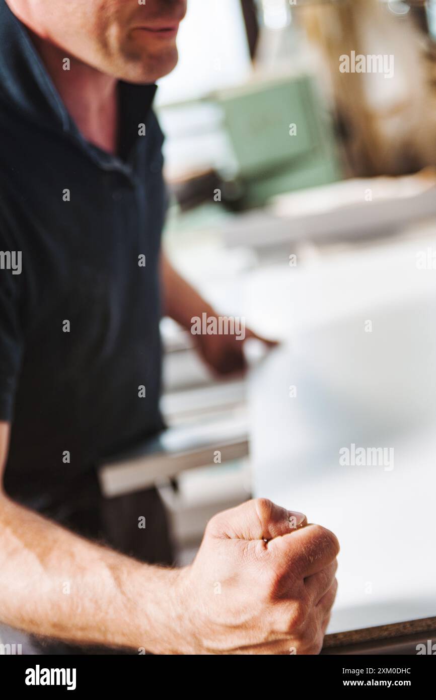 Carpenter sta stringendo il pugno in un'officina di falegnameria, mostrando la fisicità e la forza richieste in questa professione Foto Stock