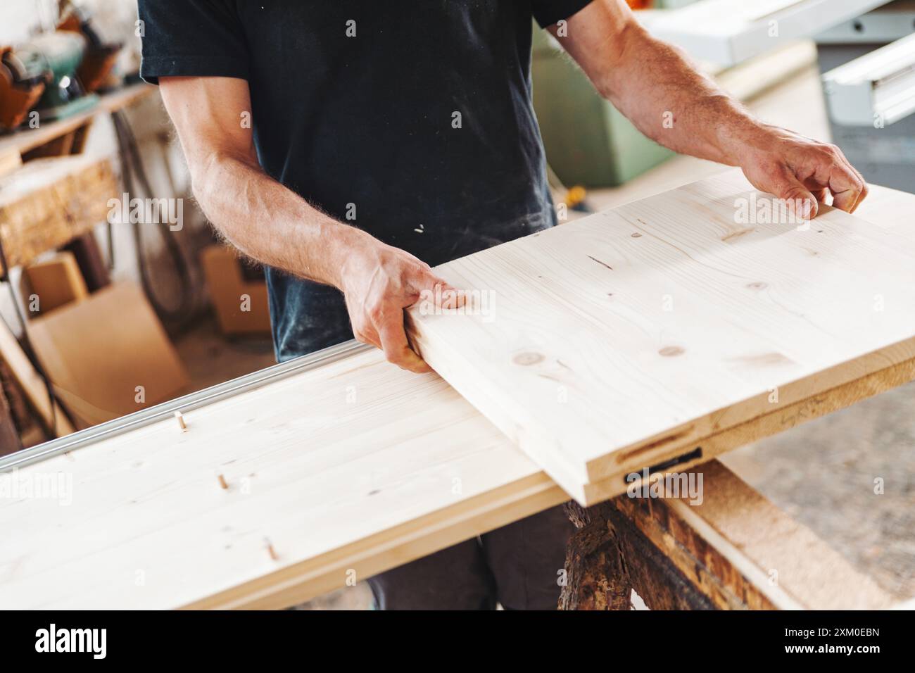 Carpenter sta unendo due tavole di legno nella sua officina, mostrando la precisione e l'abilità nella produzione di mobili artigianali Foto Stock
