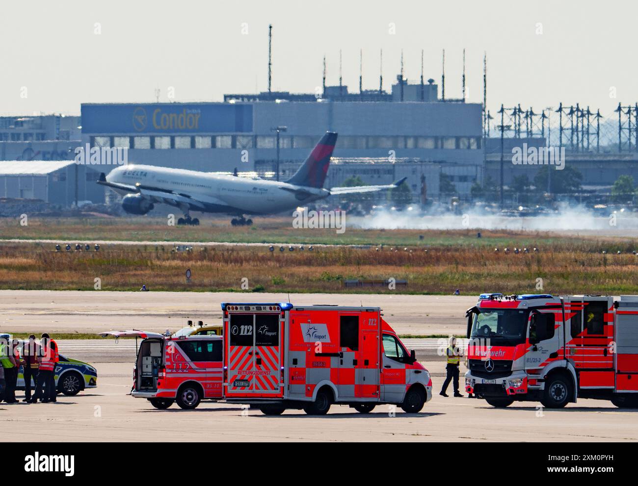 25 luglio 2024, Assia, Francoforte sul meno: Mentre la polizia e i vigili del fuoco dell'aeroporto stanno ancora affrontando gli attivisti per il clima, un aereo sta già atterrando. Gli attivisti dell'ultima generazione hanno nuovamente invaso un aeroporto. Il traffico aereo del più grande aeroporto tedesco, l'aeroporto Reno-meno, è stato temporaneamente sospeso. Il traffico aereo è in fase di ripresa. Foto: Andreas Arnold/dpa Foto Stock