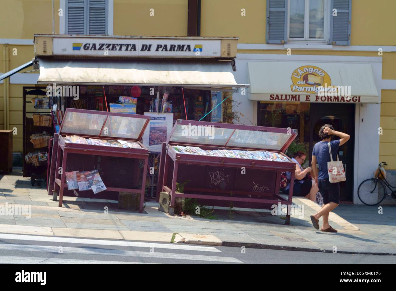 Parma, Italia 24 luglio 2024 il turista passeggia davanti a un'edicola tradizionale italiana che espone giornali e riviste locali Foto Stock