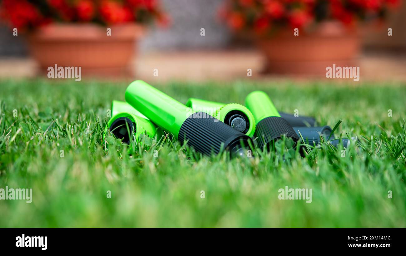 I raccordi per tubi e gli ugelli di irrigazione verdi e vibranti sono sparsi su erba morbida e sana, mettendo in mostra gli strumenti essenziali per il giardinaggio progettati per un'efficienza ottimale Foto Stock I raccordi per tubi e gli ugelli di irrigazione verdi e vibranti sono sparsi su erba morbida e sana, mettendo in mostra gli strumenti essenziali per il giardinaggio progettati per un'efficienza ottimale Foto Stock