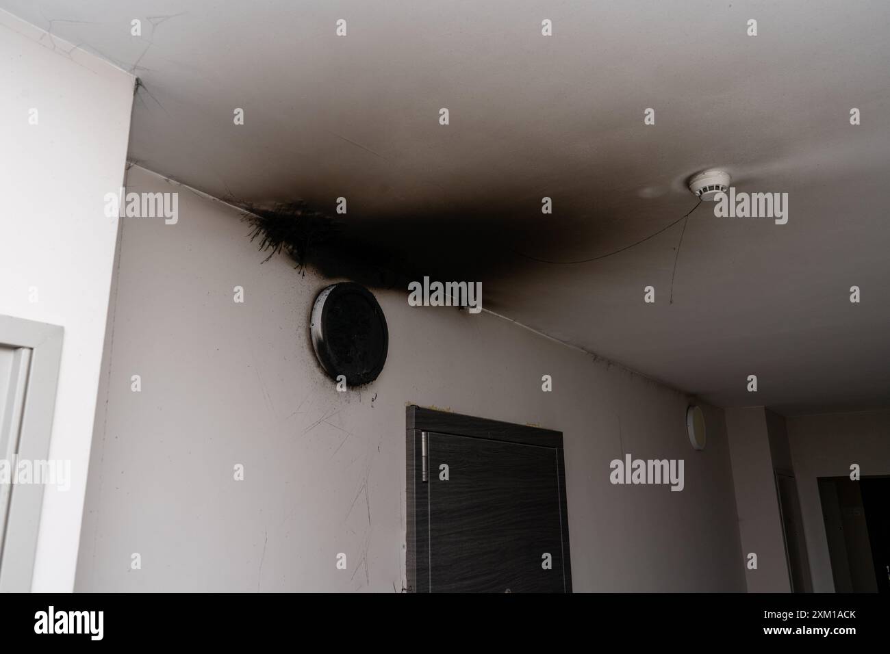 Lampada LED bruciata. Una lampada a paralume sulla parete dopo un incendio. Combustione spontanea e incendio in un edificio residenziale. Sensore di allarme antincendio interno Foto Stock