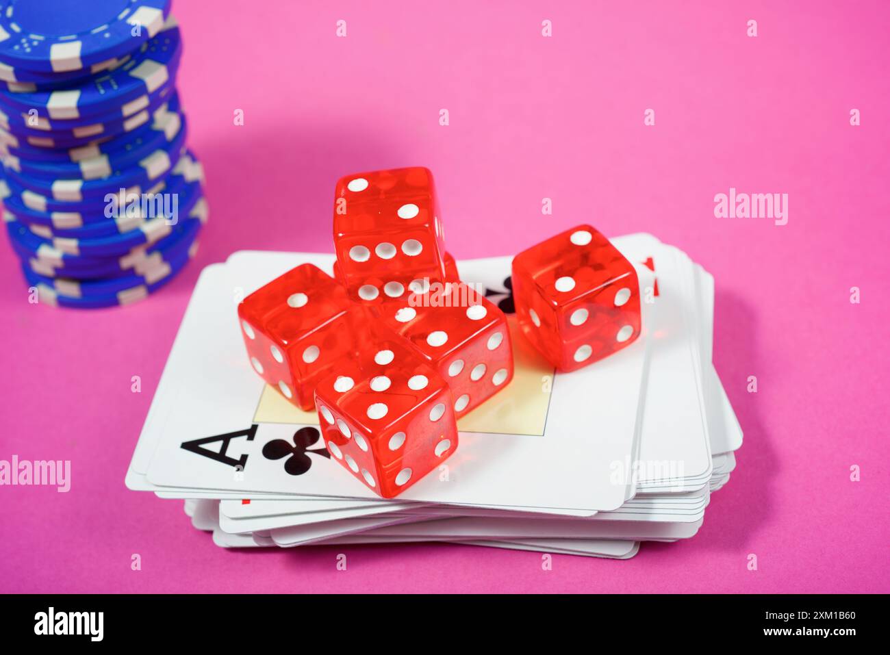 Primo piano di un gruppo di chip del casinò, carte da poker e dadi su un tavolo rosa Foto Stock