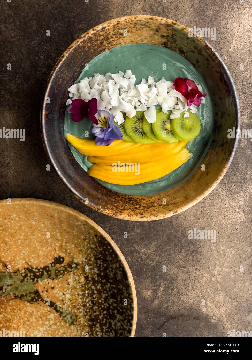 Ciotola per frullati Spirulina con kiwi di mango e fiocchi di cocco, splendidamente decorata. Foto Stock