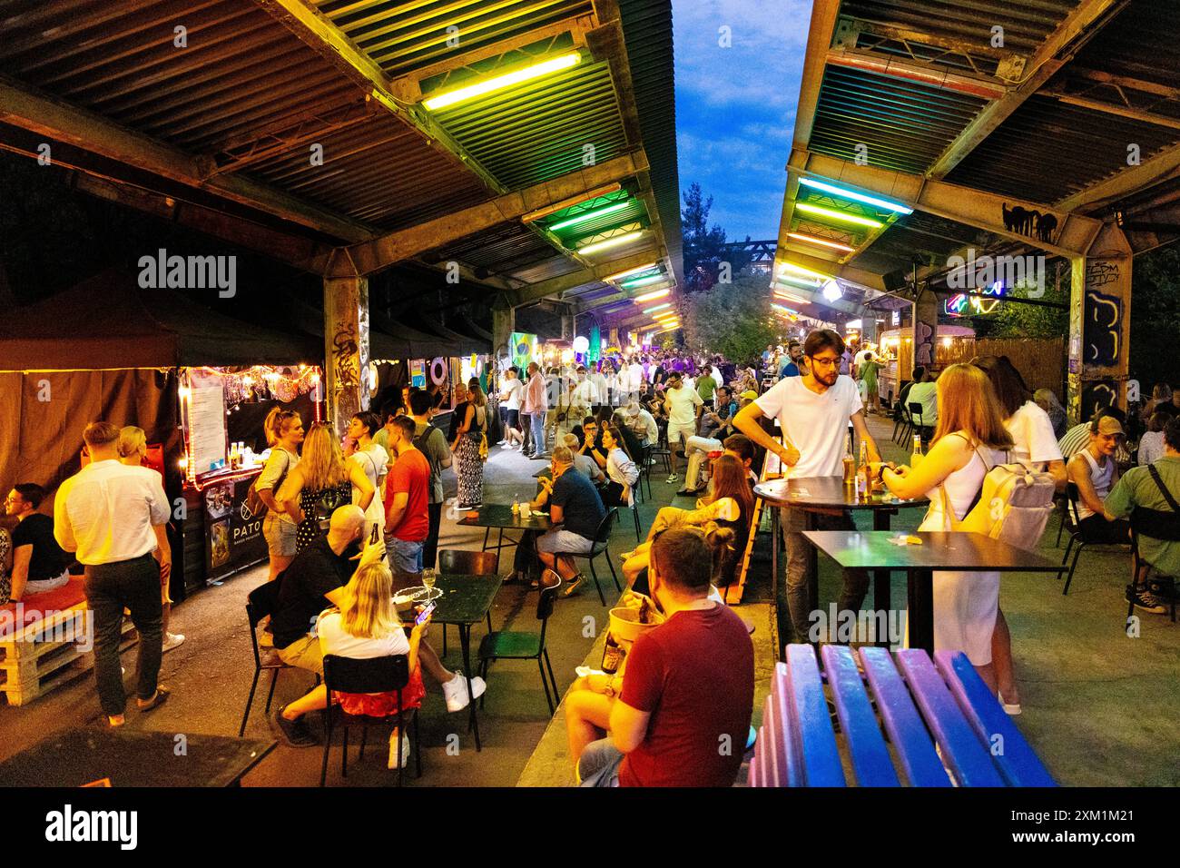 Persone che mangiano al mercato alimentare all'aperto di Nocny Market (mercato notturno) all'interno delle ex piattaforme della stazione ferroviaria centrale, Varsavia, Polonia Foto Stock