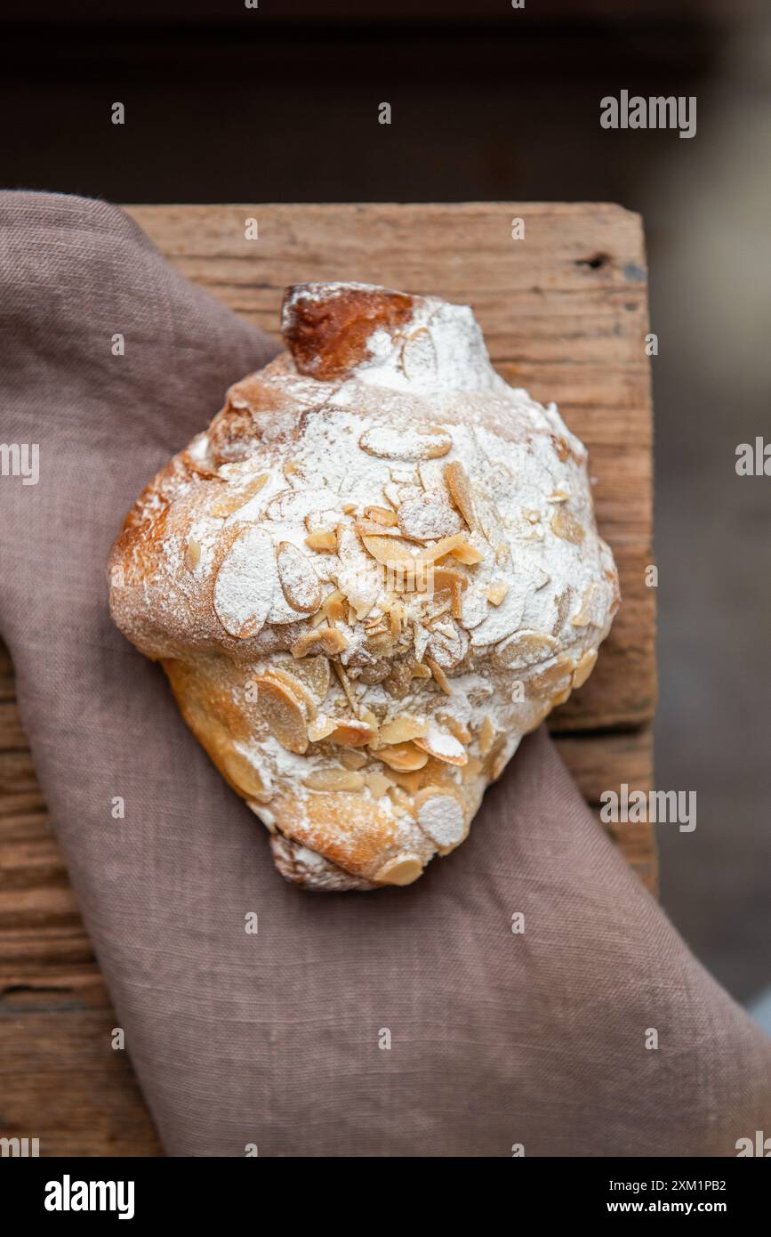 Croissant alle mandorle appena sfornato con noci su un tavolo di legno. Vista dall'alto Foto Stock