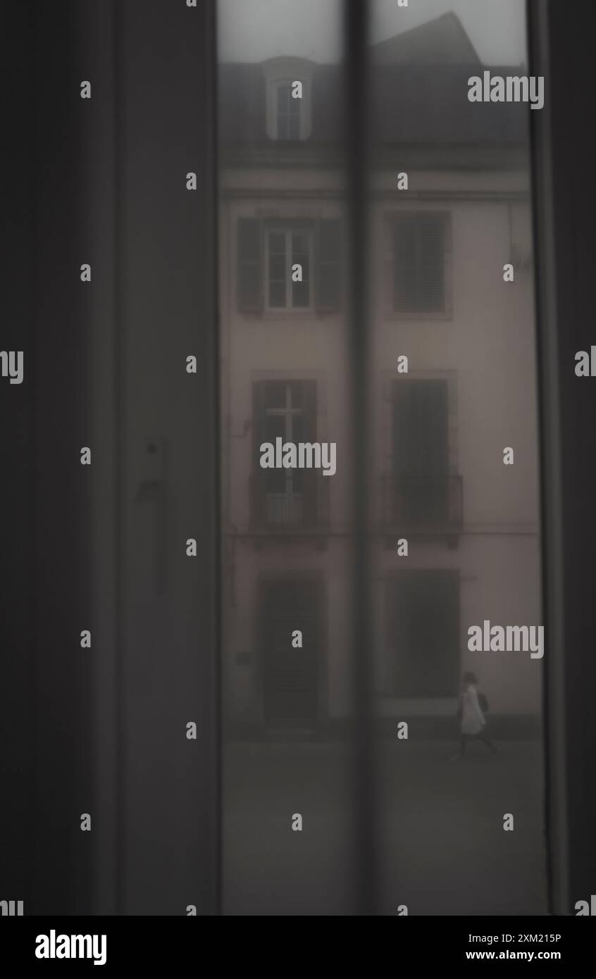 Il paesaggio sfocato, suggestivo e romantico si affaccia sulla strada attraverso le tende di una signora che cammina in una strada europea Foto Stock