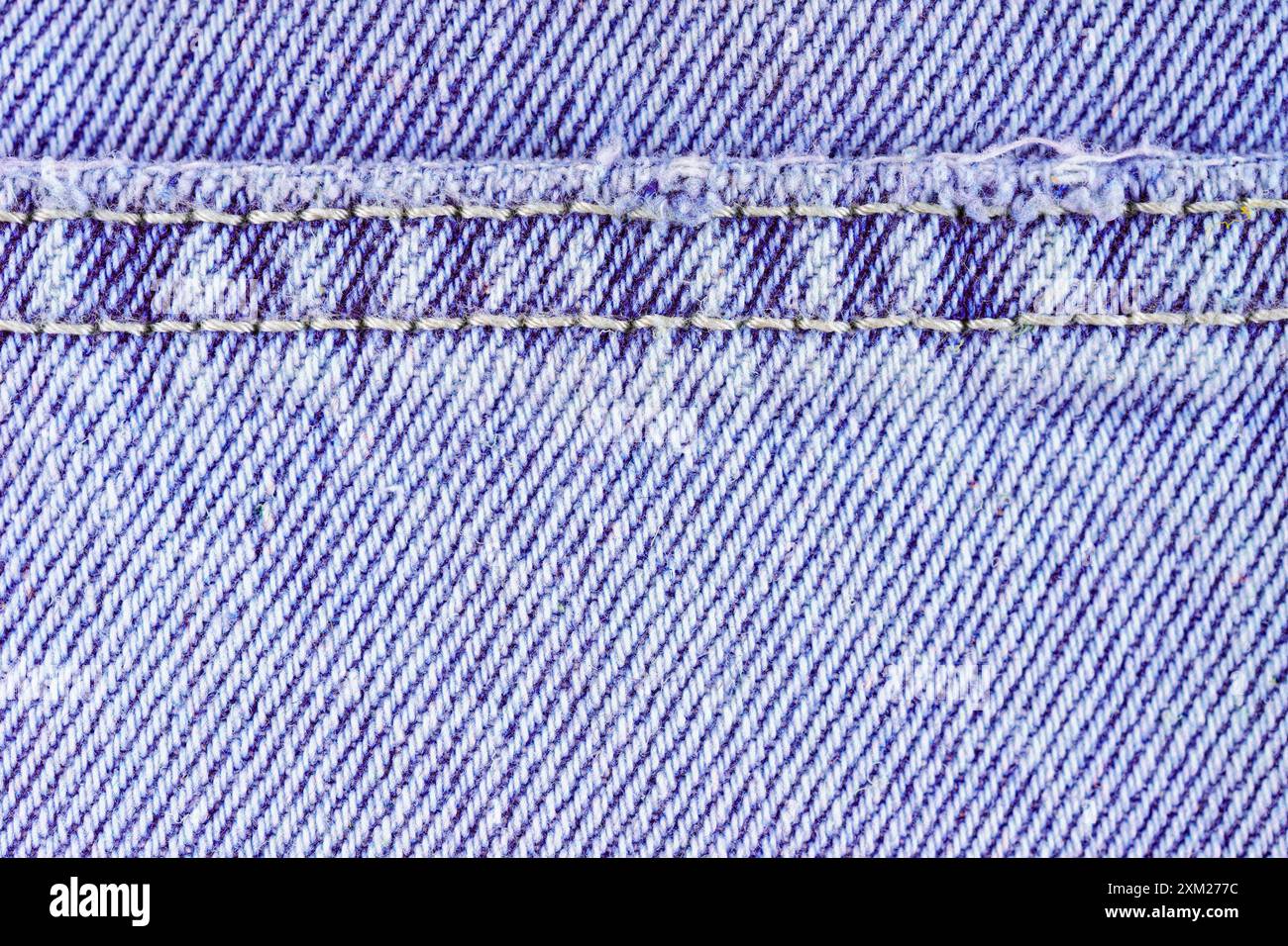 Pantaloni in jeans viola con cuciture, primo piano, effetto macro. Carta da parati in tessuto, sfondo, dettagli di design. Foto Stock