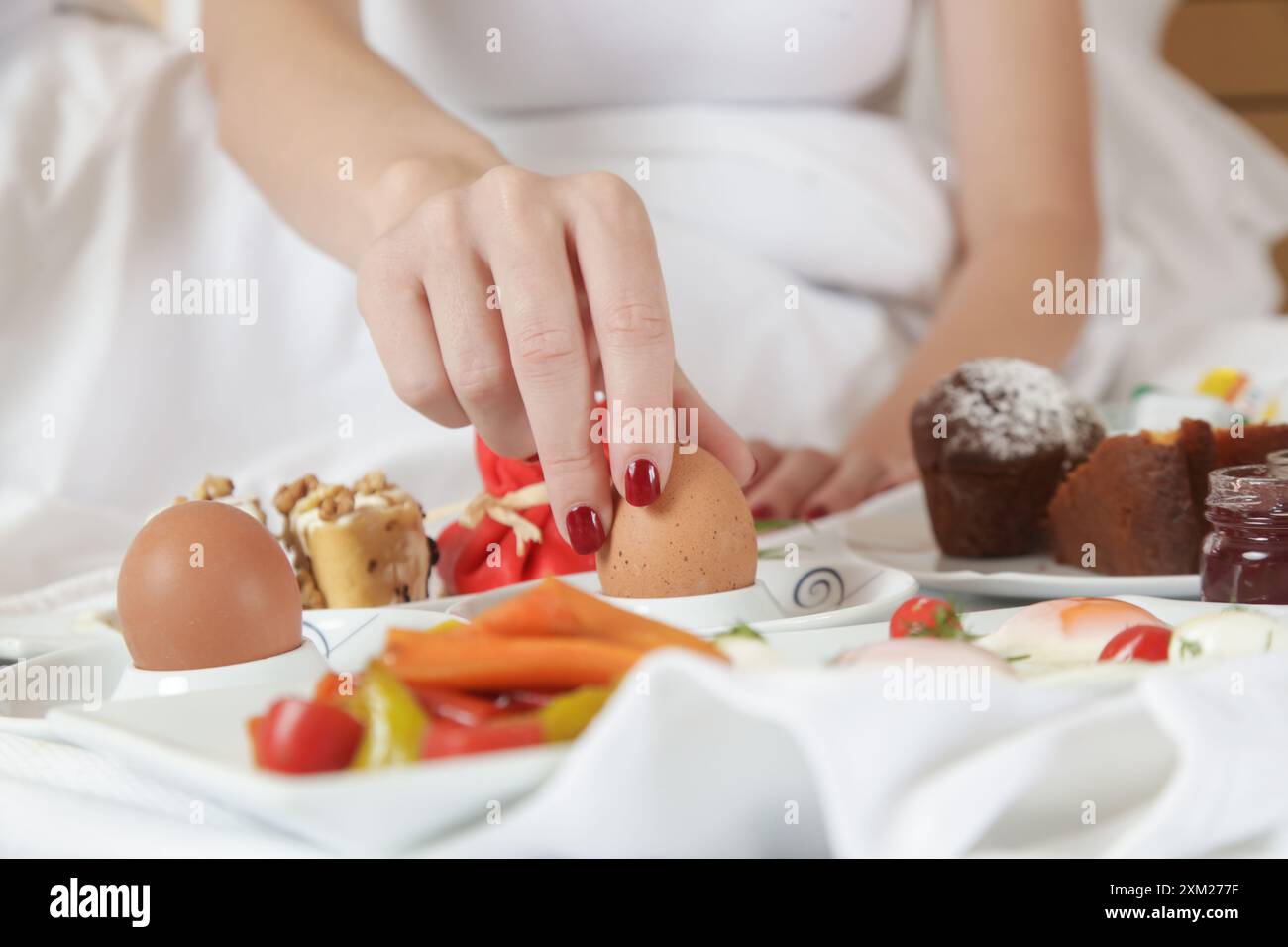 Giovane donna che fa colazione nel letto. Mattinata tranquilla e idilliaca a casa o in camera d'hotel Foto Stock