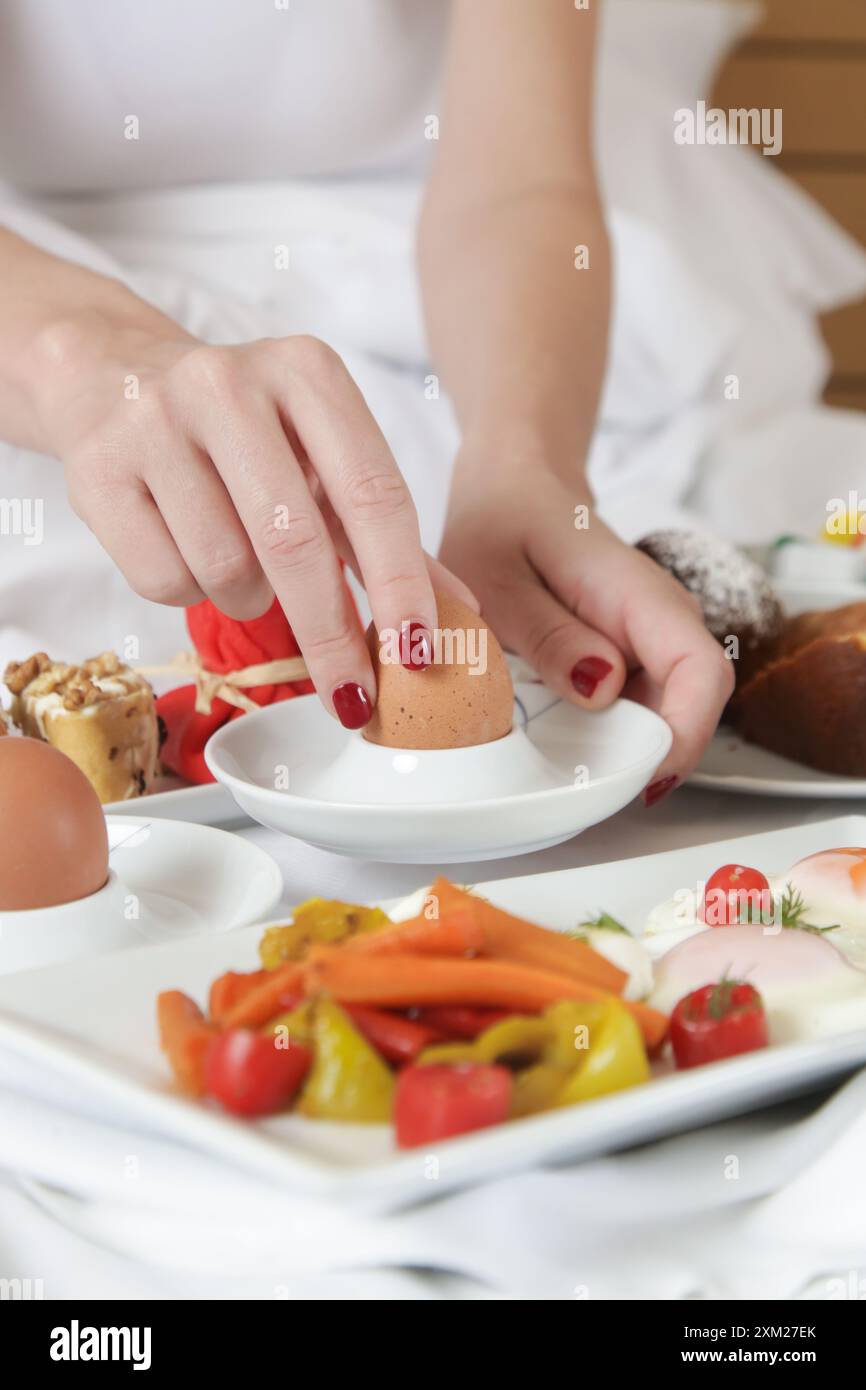 Giovane donna che fa colazione nel letto. Mattinata tranquilla e idilliaca a casa o in camera d'hotel Foto Stock