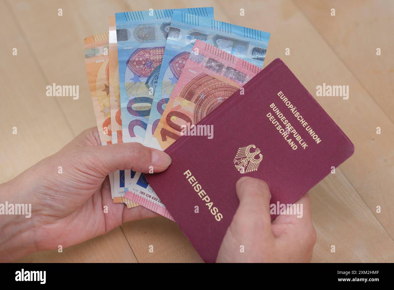 Hand hŠlt einen deutschen Reisepass und Euroscheine *** Hand possiede un passaporto tedesco e banconote in euro Foto Stock