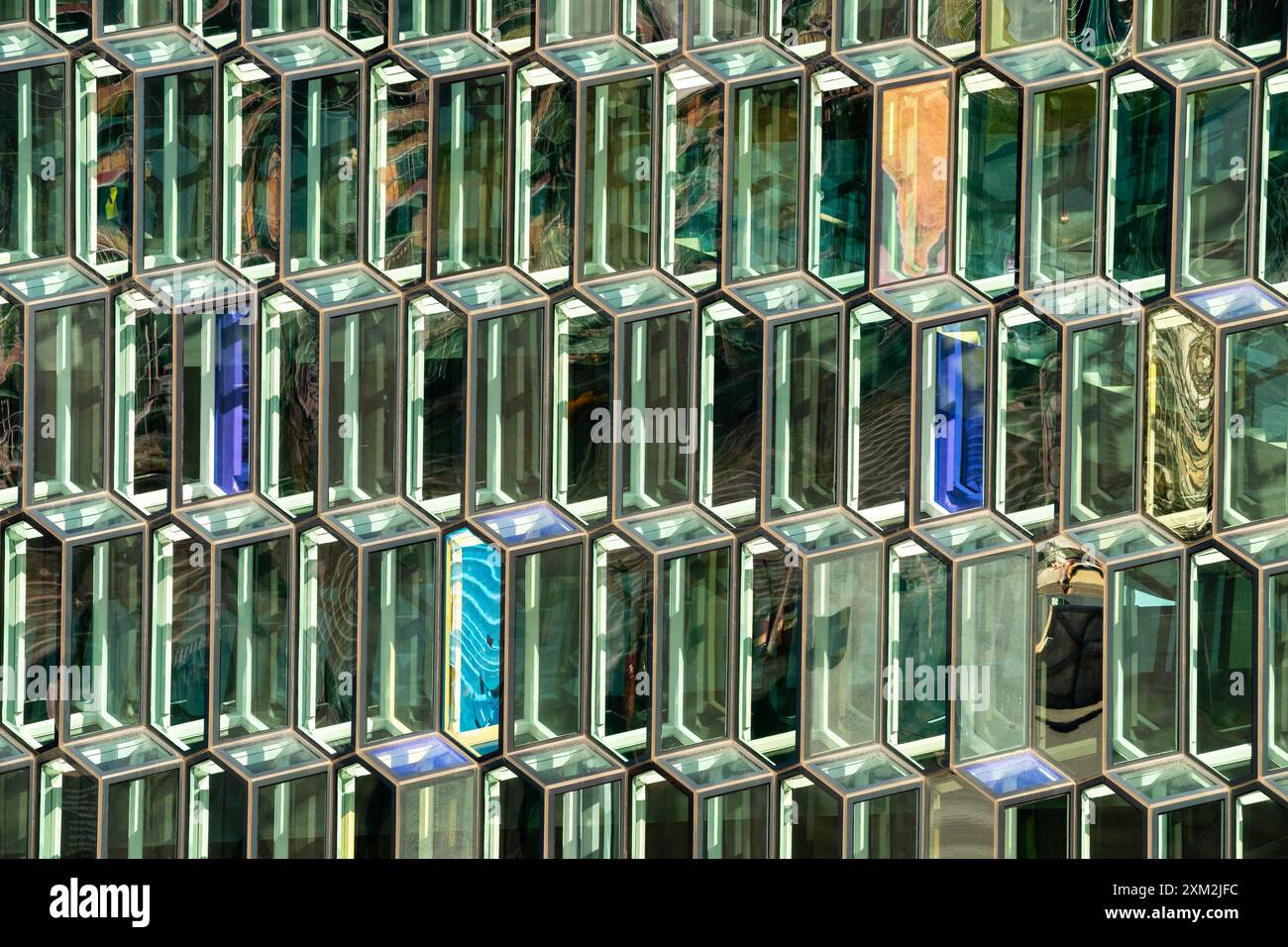 Finestre in vetro geometrico astratto che riflettono la luce del sole sulla facciata dell'edificio moderno Foto Stock