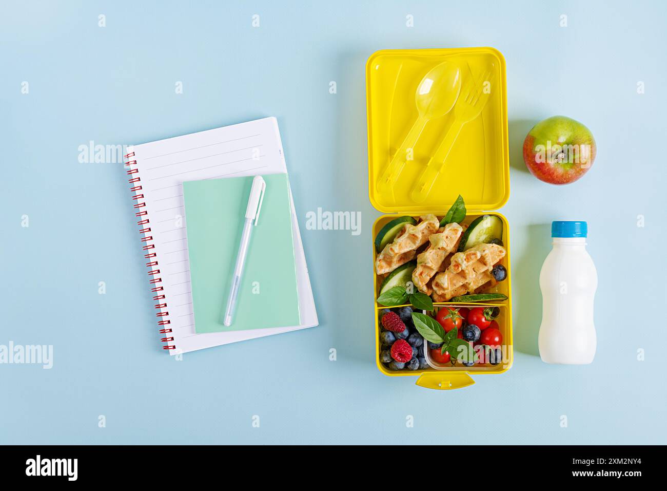 Pranzo al sacco per bambini con zucchine, cetrioli, pomodori ciliegini e mirtilli. Ritorno a scuola per la colazione. Copia spazio. Vista dall'alto, disposizione piatta Foto Stock