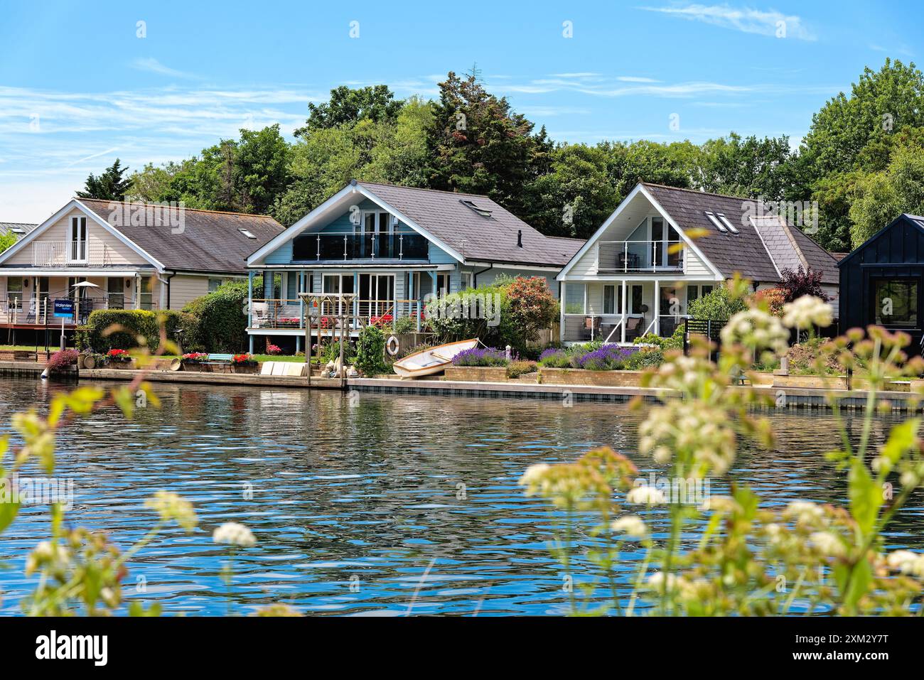 Moderne case lungo il fiume sulla tenuta di River Ash a Shepperton, viste dall'altra parte del Tamigi da Walton in un giorno di sole estati, Surrey, Inghilterra, Regno Unito Foto Stock