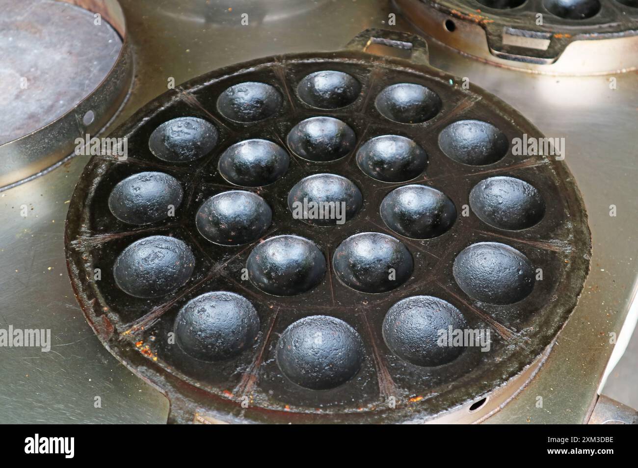 Teglia in ghisa riscaldata per preparare pancake tailandesi al latte di cocco chiamati Kanom Krok Foto Stock