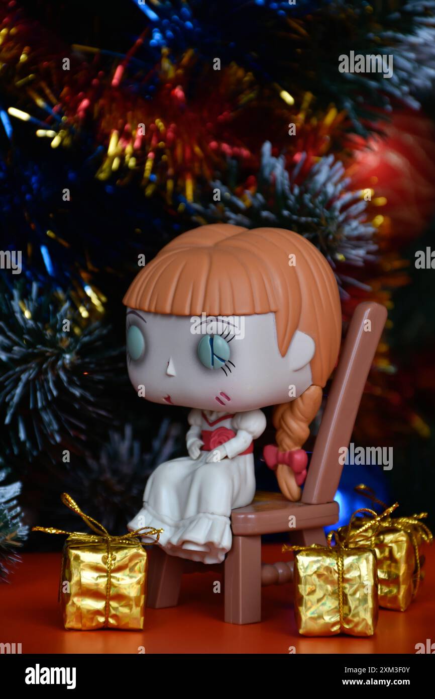 Funko Pop action figure di bambola infestata Annabelle seduta sulla sedia di film horror sovrannaturali Conjuring. Albero di Natale, scatole regalo d'oro. Foto Stock