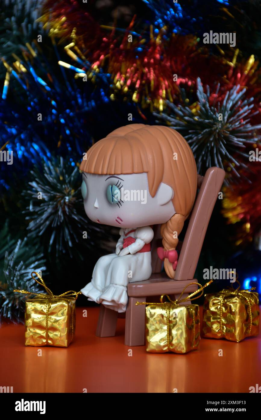 Funko Pop action figure di bambola infestata Annabelle seduta sulla sedia di film horror sovrannaturali Conjuring. Albero di Natale, scatole regalo d'oro. Foto Stock