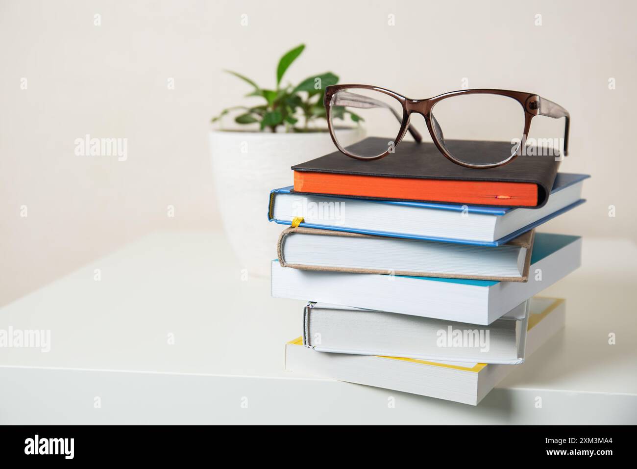 Una pila di libri con un paio di occhiali sul tavolo dello studio, spazio di copia Foto Stock