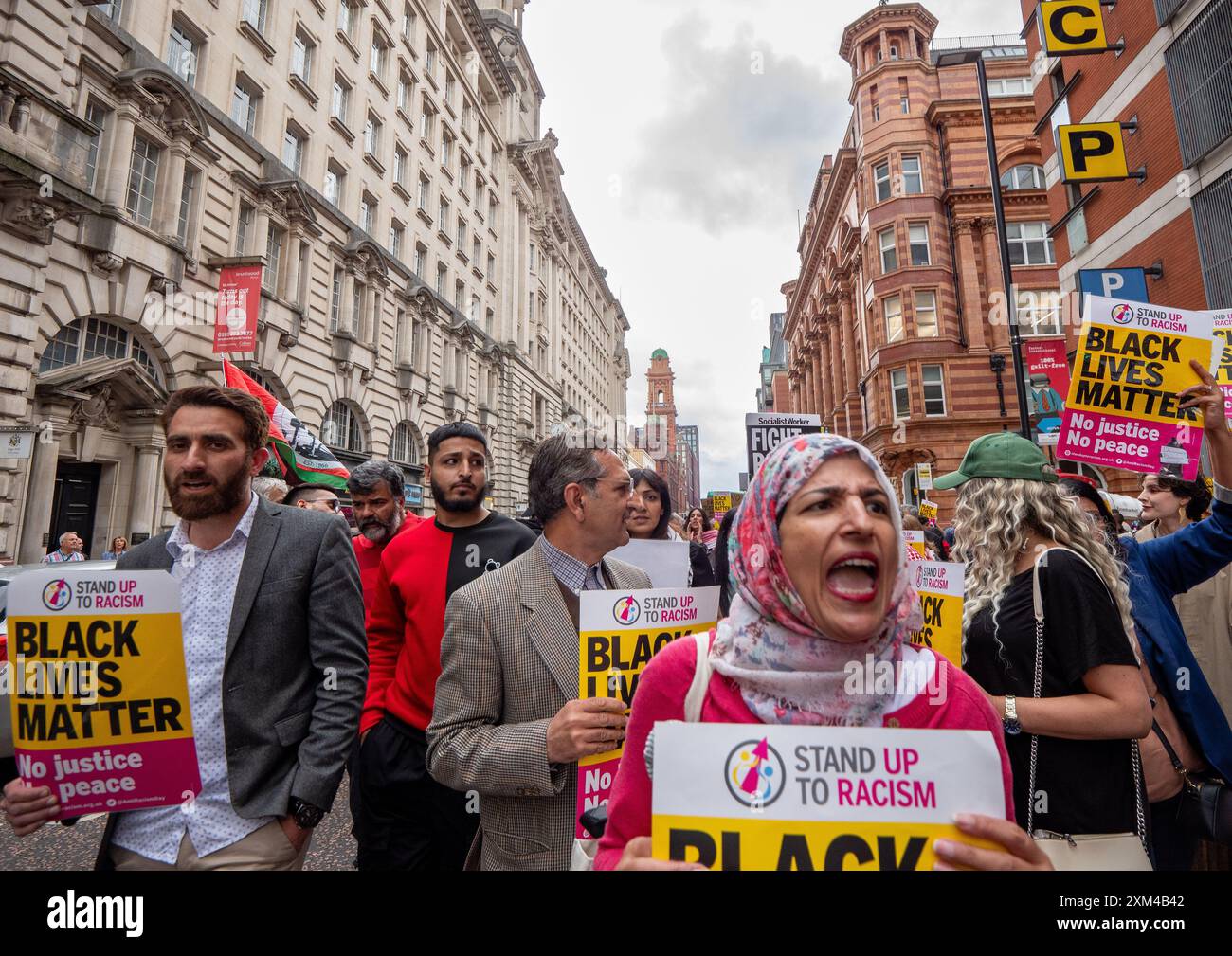 Nahella Ashraf di "Stand Up to Racism" (sciarpa da testa) guida la protesta. Greater Manchester Stand Up to Racism (GMSUTR) ha organizzato una protesta oggi presso gli uffici del sindaco della Manchester Combined Authority (GMCA) Andy Burnham su Oxford Street nella città di Manchester. I manifestanti hanno chiesto la fine immediata della violenza razzista della polizia da parte della Greater Manchester Police (GMP) a seguito di un video di recente diffusione catturato martedì sera al Terminal 2 dell’aeroporto di Manchester. Il filmato cattura un ufficiale che prende a calci in faccia un membro del pubblico seguito dall'ufficiale che timbra l'individuo Foto Stock