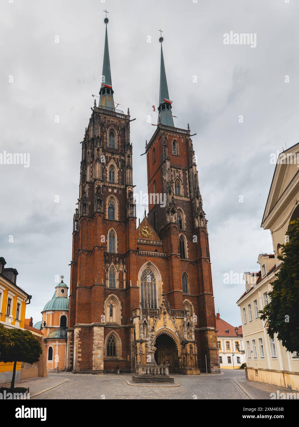 Vista frontale di una cattedrale gotica di Breslavia, Polonia, che mostra intricati dettagli architettonici e significato storico sotto un cielo nuvoloso. Foto Stock