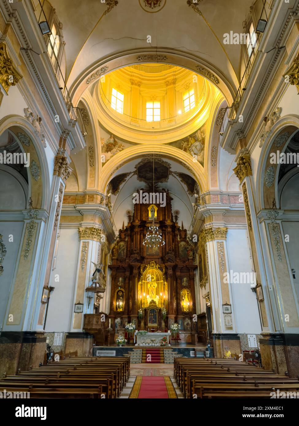 Vista interna di una grande chiesa storica con decorazioni ornamentali, soffitti a volta e un elaborato altare, che mostra l'architettura religiosa e il patrimonio culturale. Foto Stock