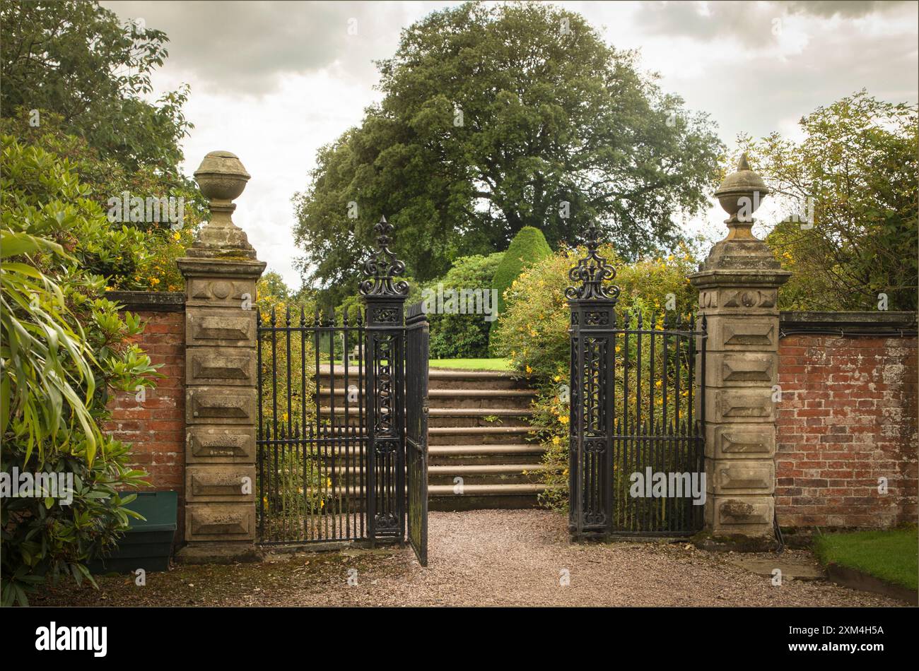 Arley, West Cheshire, Regno Unito - 17 luglio 2024 - porta d'ingresso di vecchi cancelli in arenaria che conducono a gradini in un giardino Foto Stock