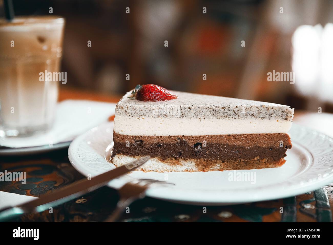 Alanya, Turchia, 17 settembre 2020: Torta al cioccolato alla fragola con cappuccino su un tavolo di legno in una caffetteria Foto Stock
