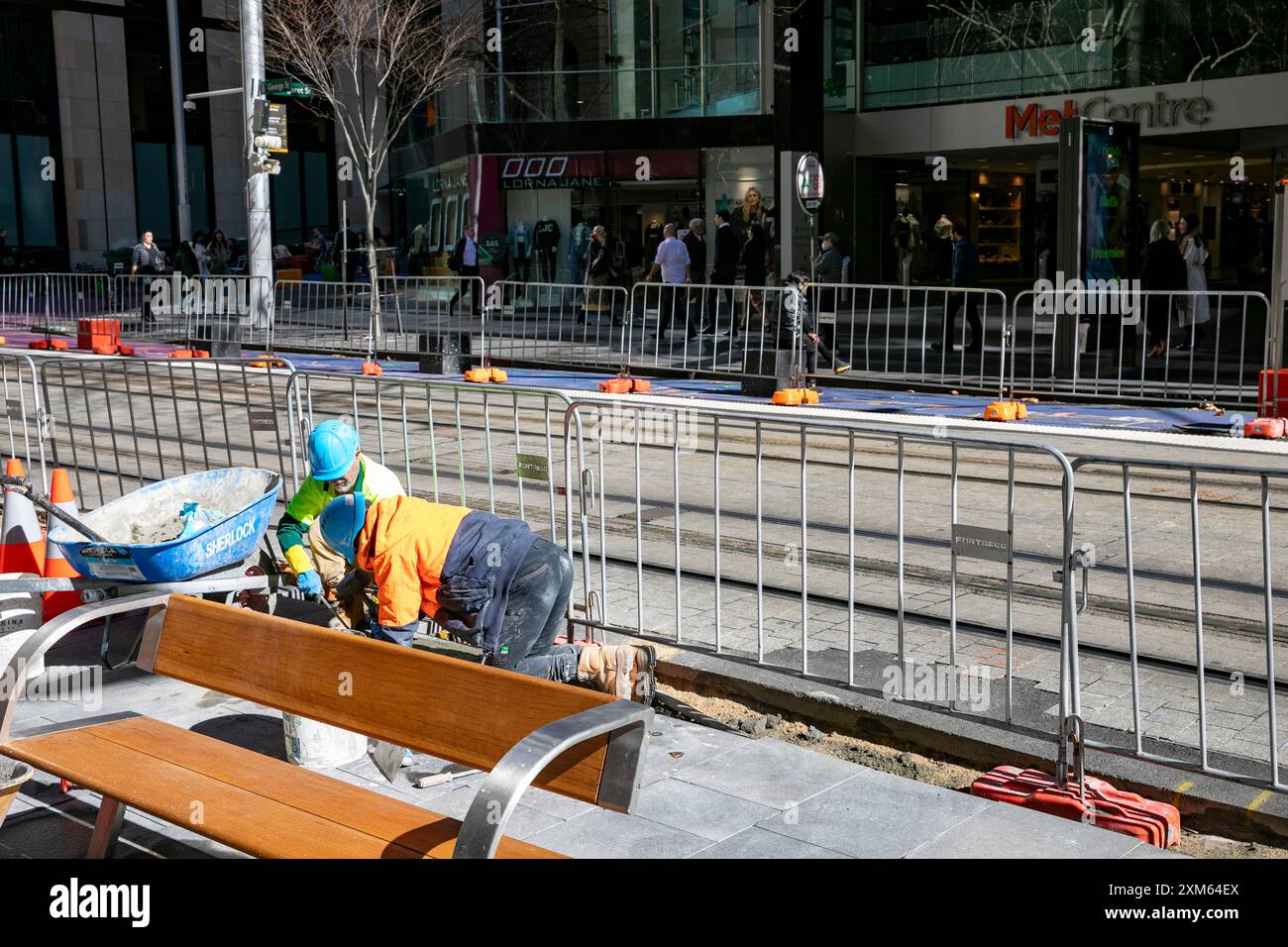 Sydney, Australia, il consiglio commercia persone che costruiscono un nuovo sentiero lungo George Street nel centro della città, lavorando in ginocchio per posare lastre Foto Stock