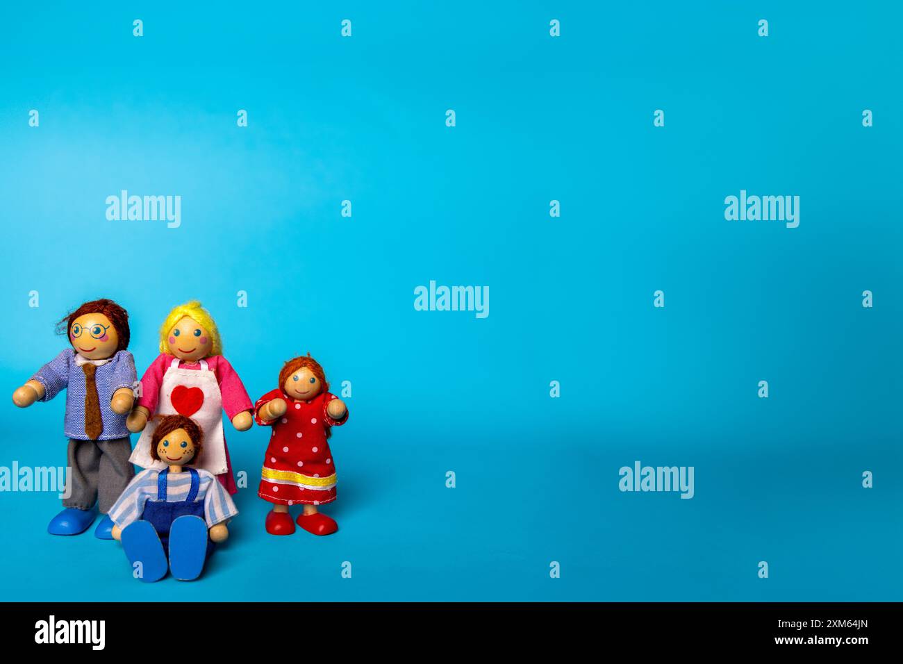 Giocattoli di legno che mostrano una famiglia di quattro persone in un ambiente blu. I giocattoli includono un padre, una madre, un figlio e una figlia, catturando la vita familiare in un semplice fascino Foto Stock