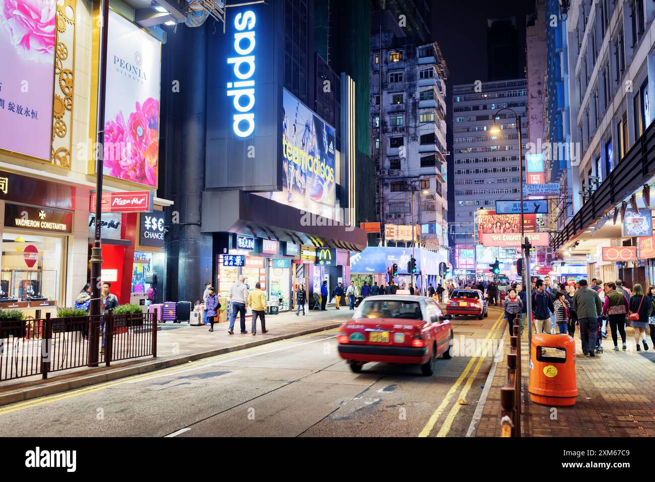 Taxi e cartelli illuminati sulla strada della città notturna di Hong Kong Foto Stock