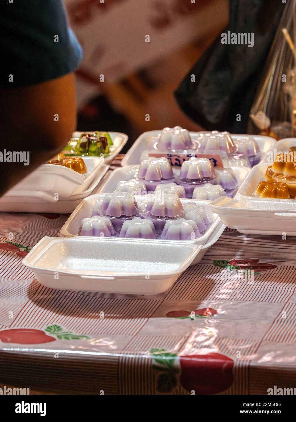 Dessert viola e bianco in contenitori in polistirolo in un mercato tailandese. Foto Stock