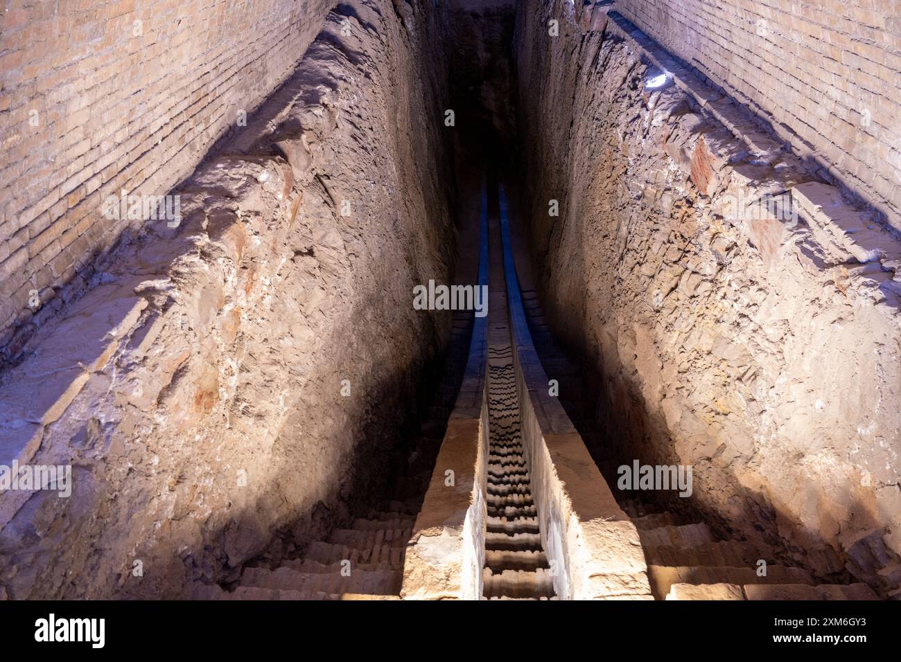 Un tunnel lungo e stretto con una scala che conduce in basso Foto Stock