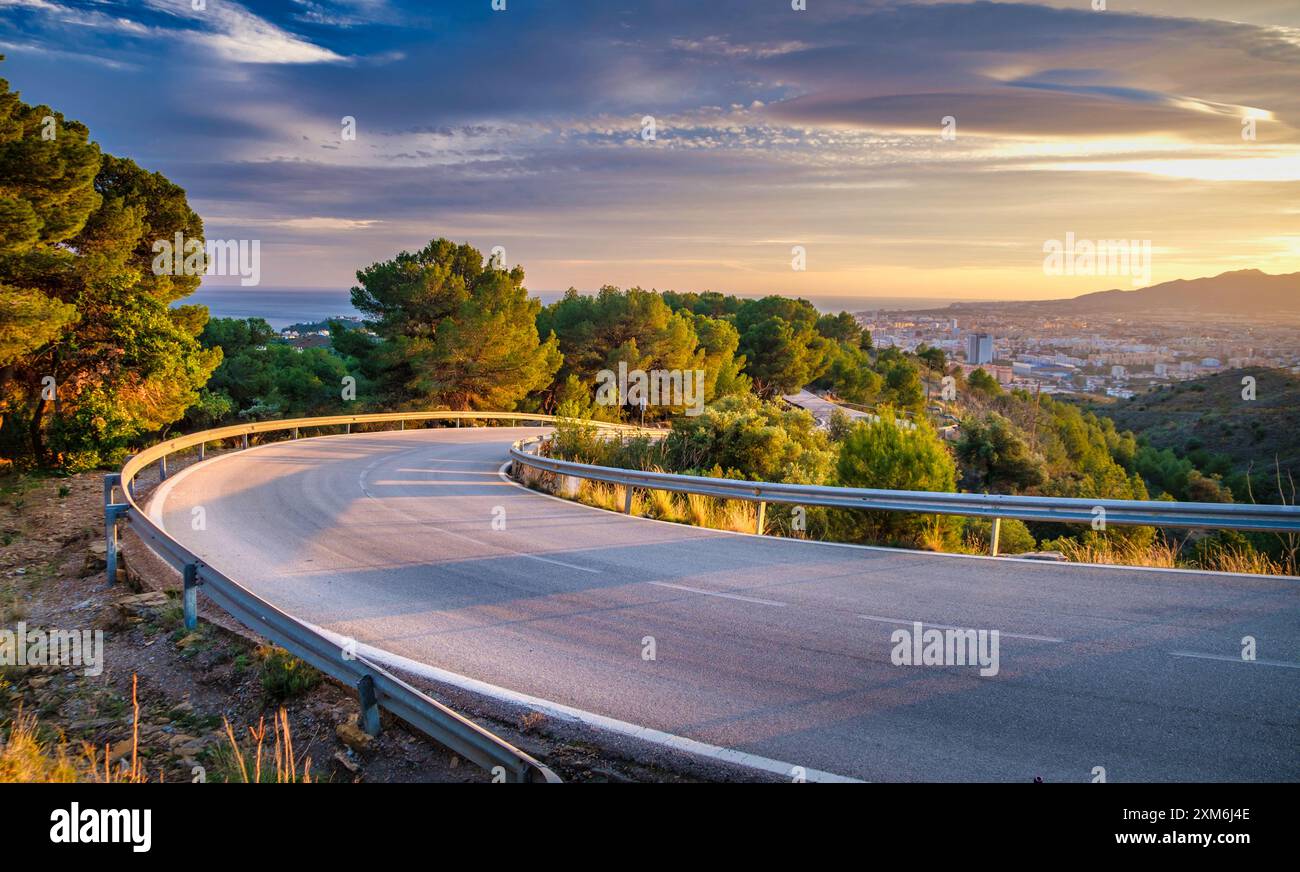 strada tortuosa che curva dolcemente a sinistra mentre si snoda attraverso un paesaggio panoramico. La strada è delimitata da barriere di sicurezza ed è circondata Foto Stock