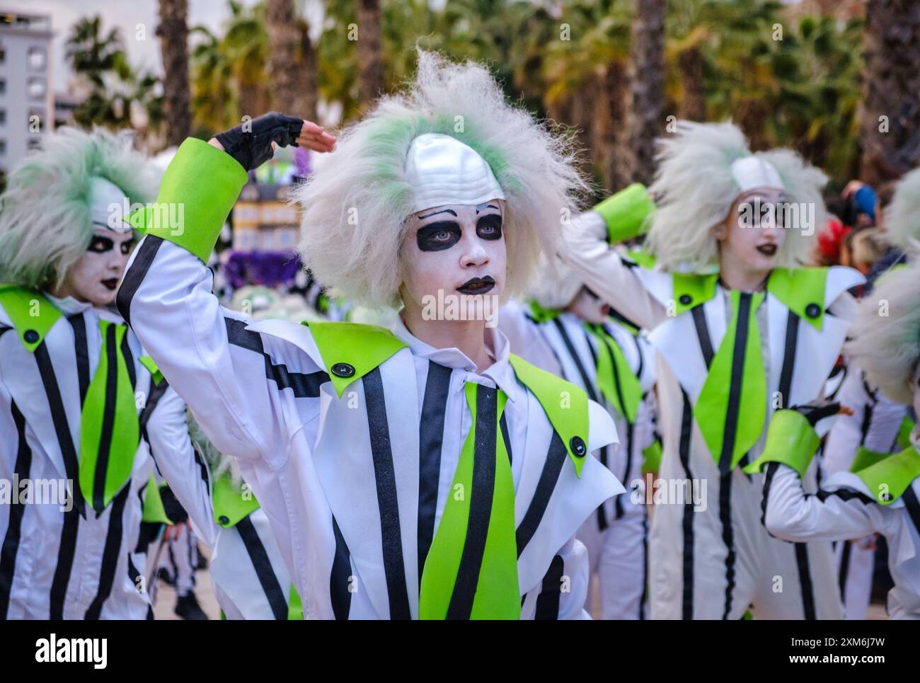 Prestazioni sincronizzate da persone in costume nero, bianco e neon sotto le palme soleggiate, con trucchi e coreografie sorprendenti. Foto Stock