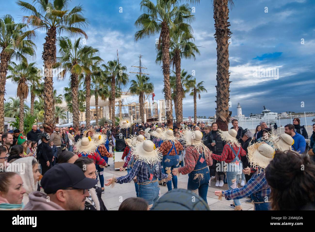 Spettacoli di danza culturale e festosa all'aperto circondati da spettatori, adagiati in uno sfondo tropicale costiero con palme e oceano. Foto Stock