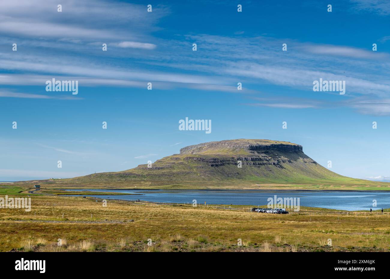 Maestosa collina con lago tranquillo e prati verdi sotto un cielo azzurro Foto Stock