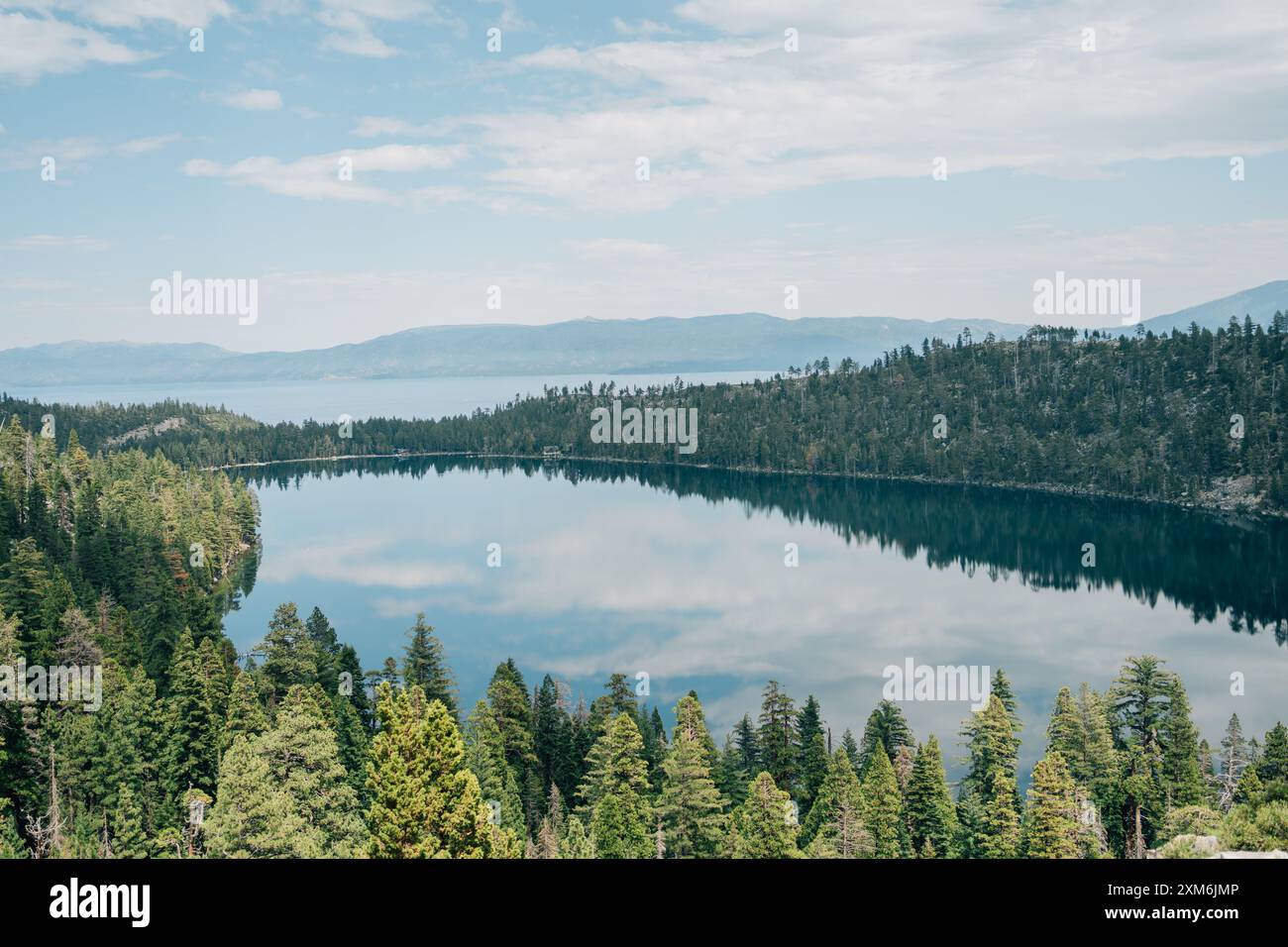 Una vista di alberi che si riflettono su un lago con montagne in lontananza Foto Stock