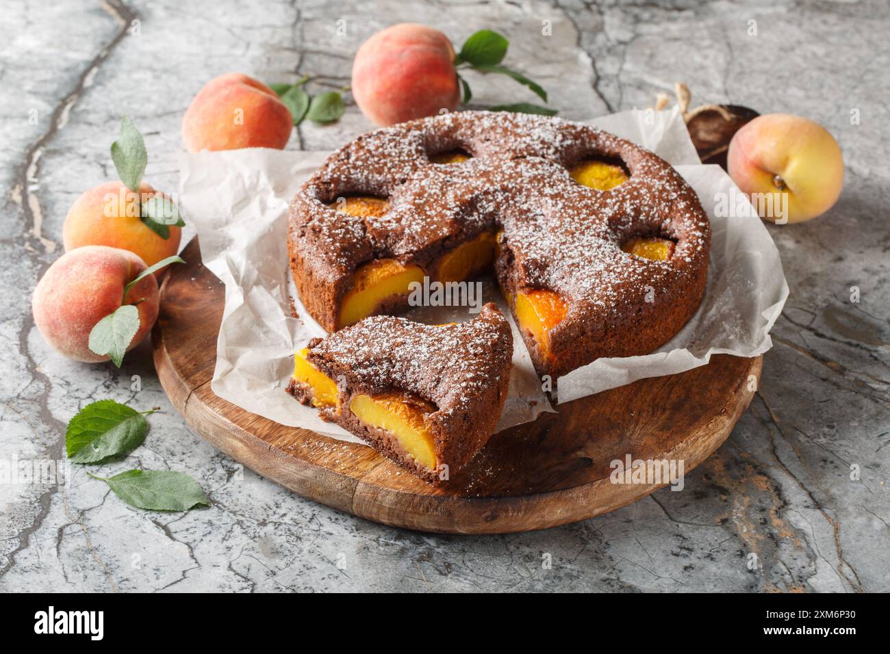 Dolce estivo con pan di Spagna al cioccolato alla frutta e pesca, primo piano su tavola di legno. Orizzontale Foto Stock