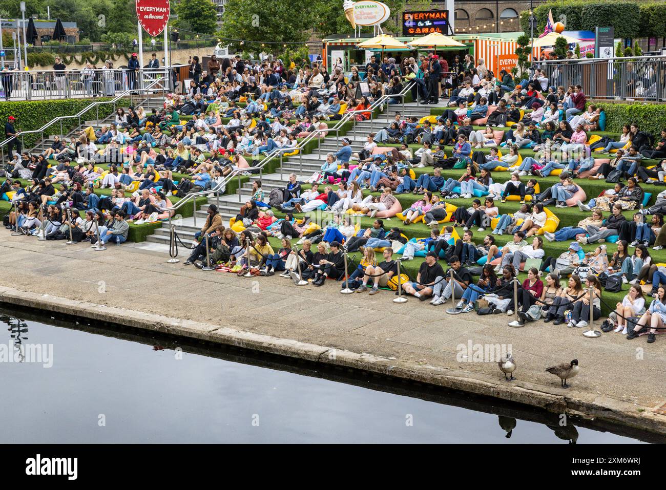 Londra, Regno Unito. 25 luglio 2024. Le persone guardano il cinema all'aperto gratuito all'Everyman on the Canal, un grande schermo installato a Granary Square Steps, King's Cross, nonostante il clima umido e mutevole di oggi, e sembrano godersi la loro estate con l'intrattenimento della città. Everyman on the Canal proietta 4 film al giorno tra il 1° luglio e il 18 agosto. Crediti: Imageplotter/Alamy Live News Foto Stock